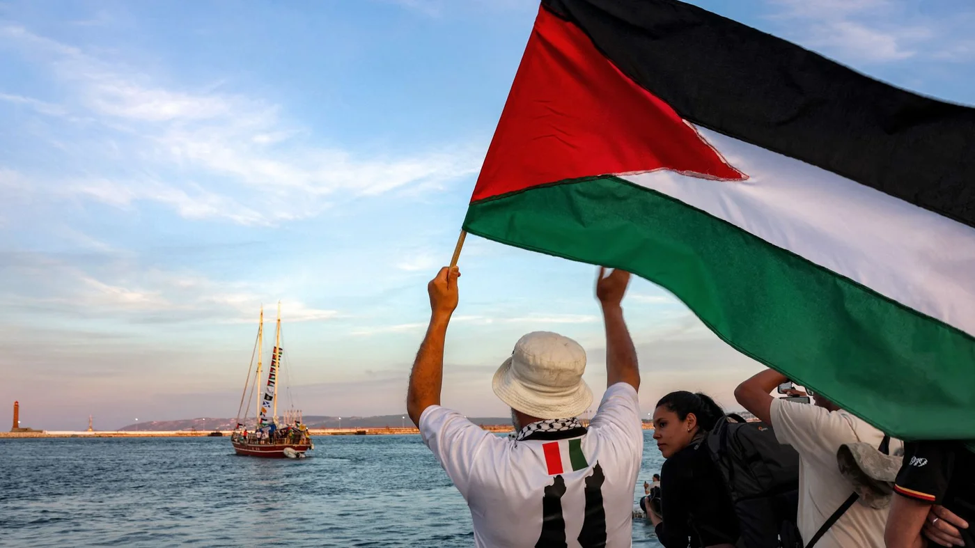 Persona ondeando una bandera palestina en una flotilla hacia Gaza